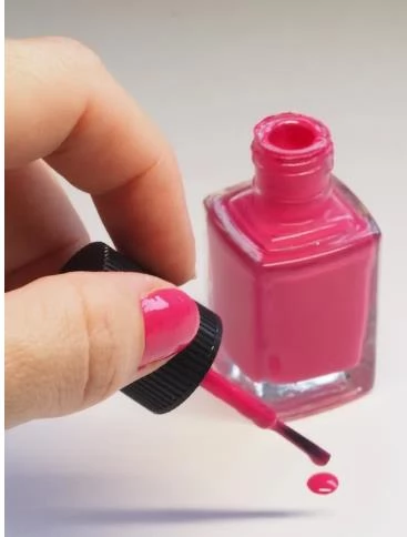 person with pink manicure on white textile